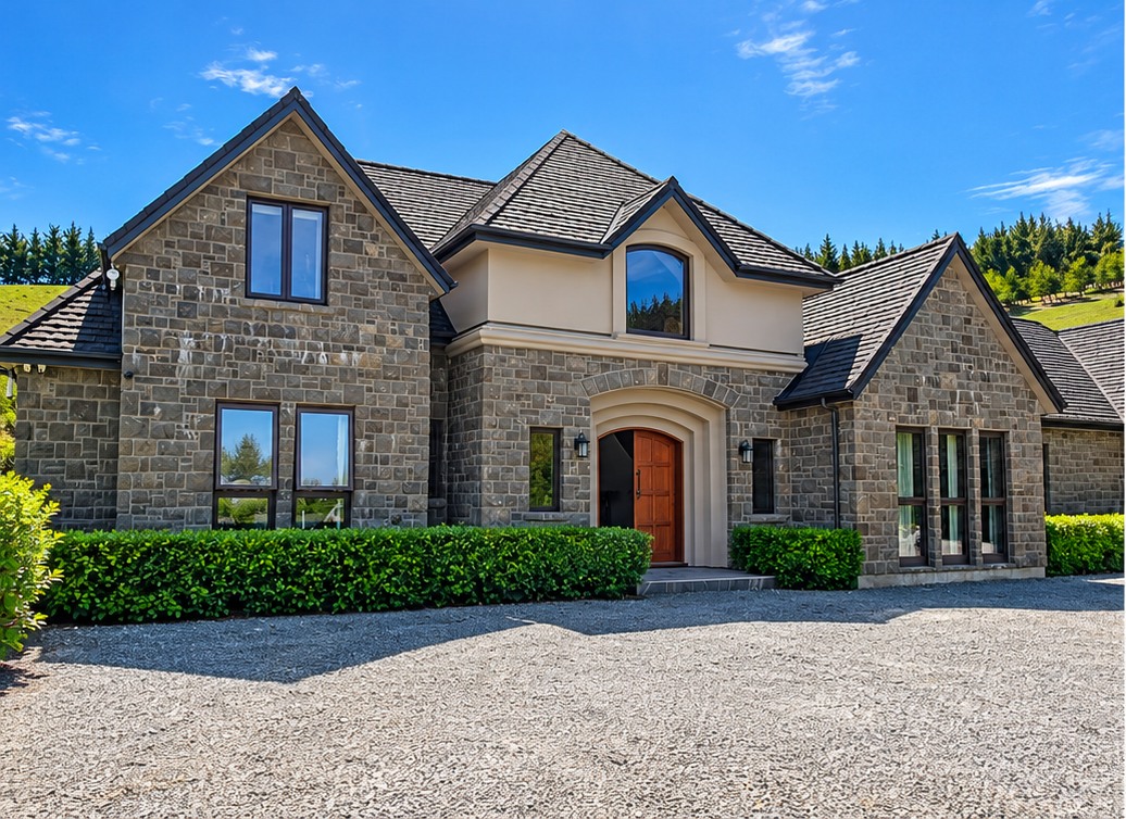 Stone residence with tall windows and a gravel driveway, vehicles removed from image